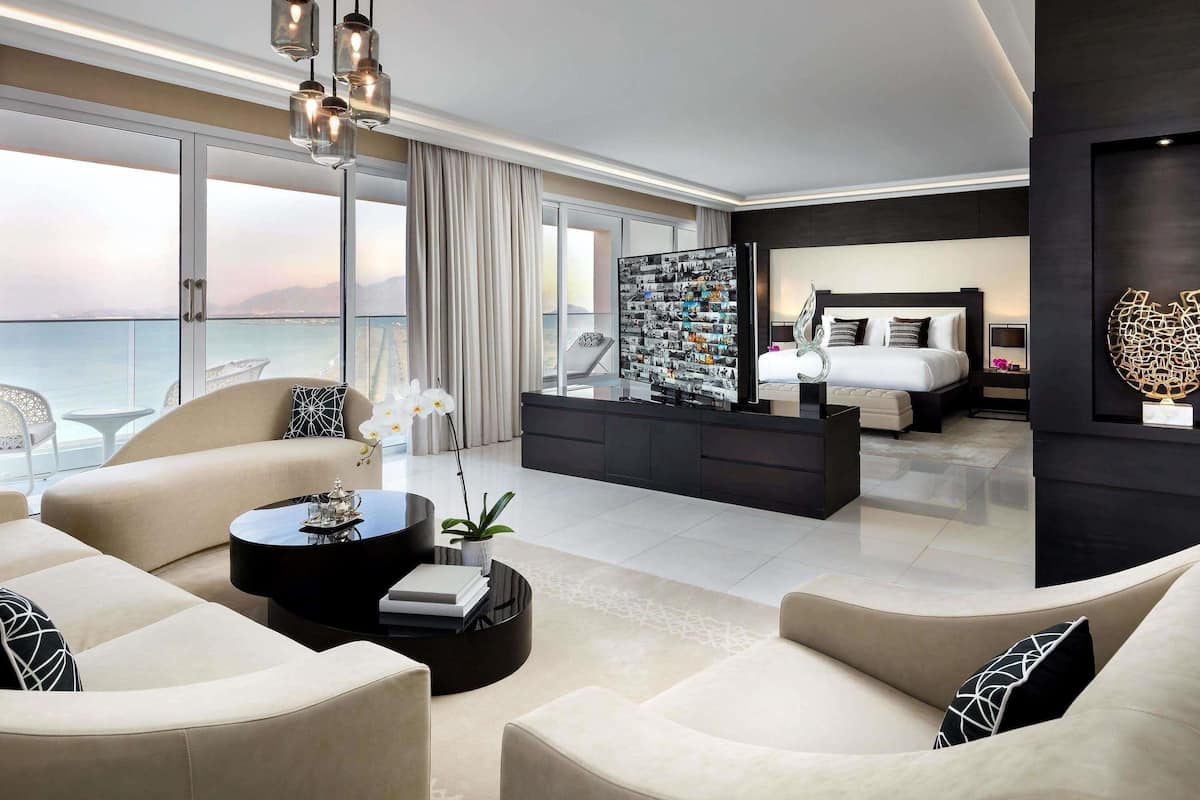 Une chambre d’hôtel moderne dotée d’un grand balcon, d’un lit avec une tête de lit, d’une table basse et d’un téléviseur fixé au mur.