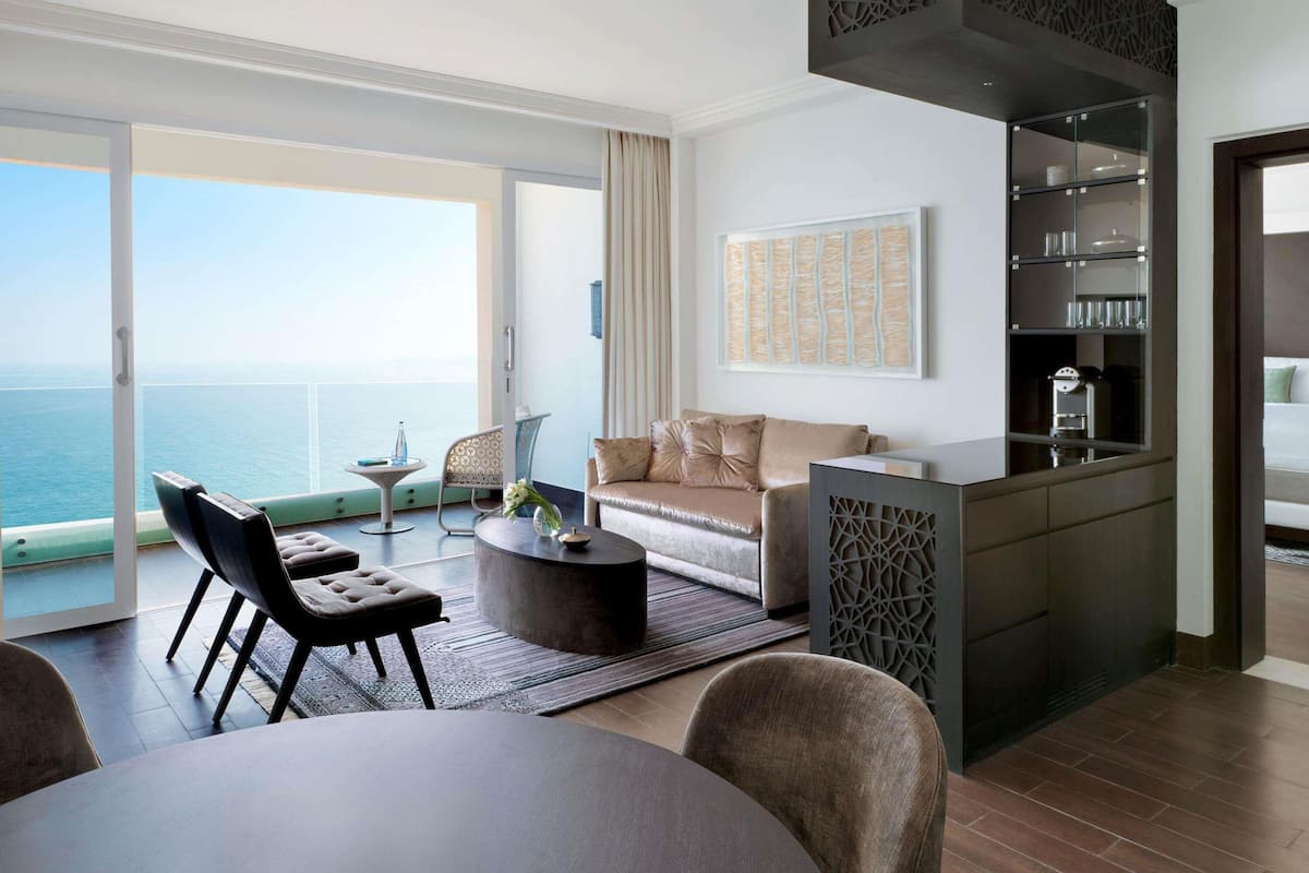 Een moderne woonkamer met een bank, stoelen, een salontafel en uitzicht op de oceaan.