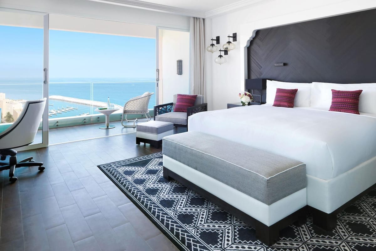 Une chambre spacieuse avec un grand lit, un balcon offrant une vue sur la mer et un aménagement moderne.