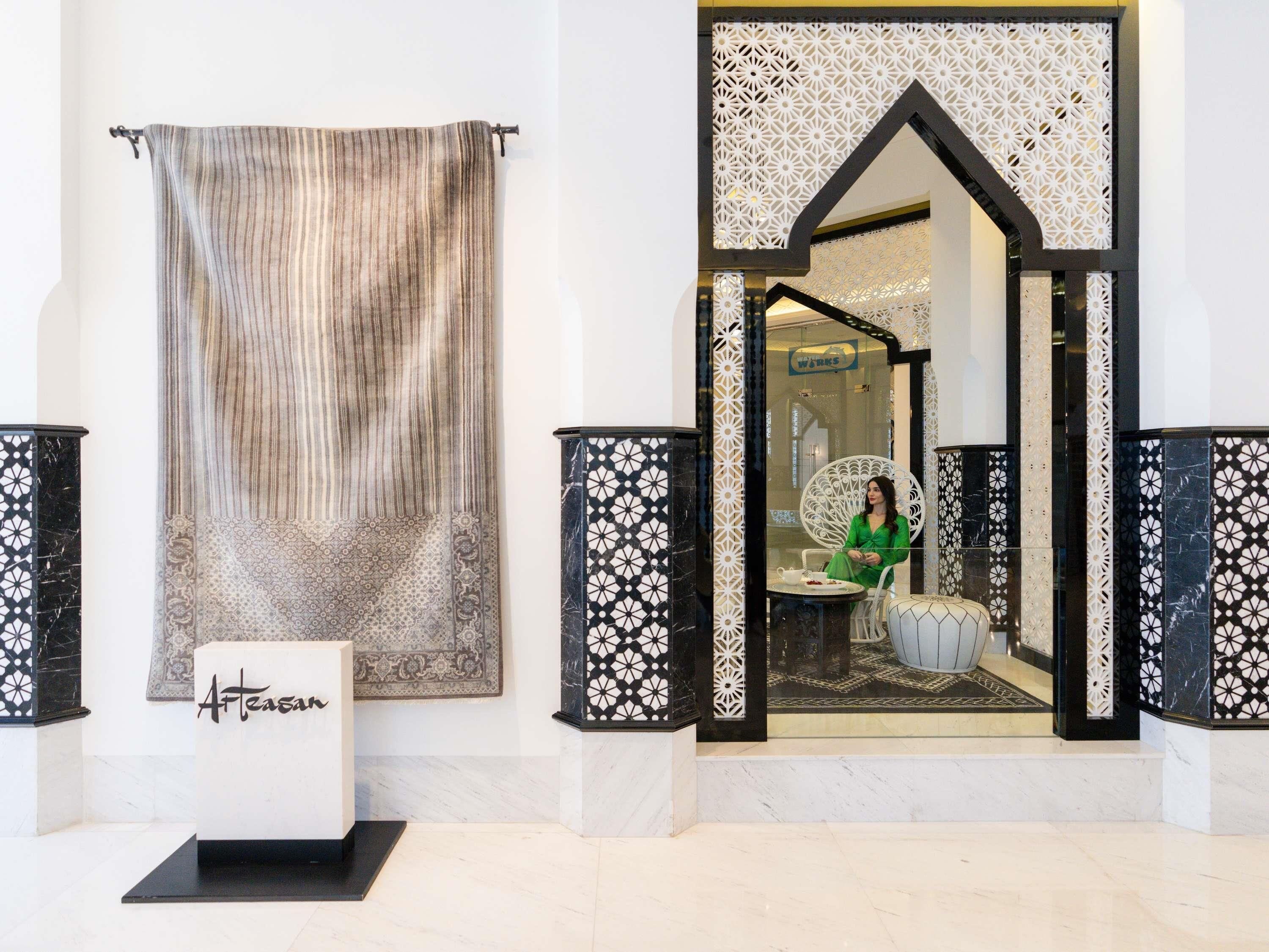 Un vestíbulo con una cortina estampada, un mostrador de recepción y una zona de estar con una silla decorativa.