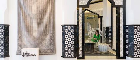 Un vestíbulo con una cortina estampada, un mostrador de recepción y una zona de estar con una silla decorativa.