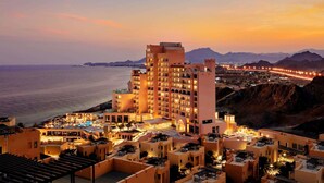Un hotel con varios pisos, piscina y vistas al mar y a las montañas.