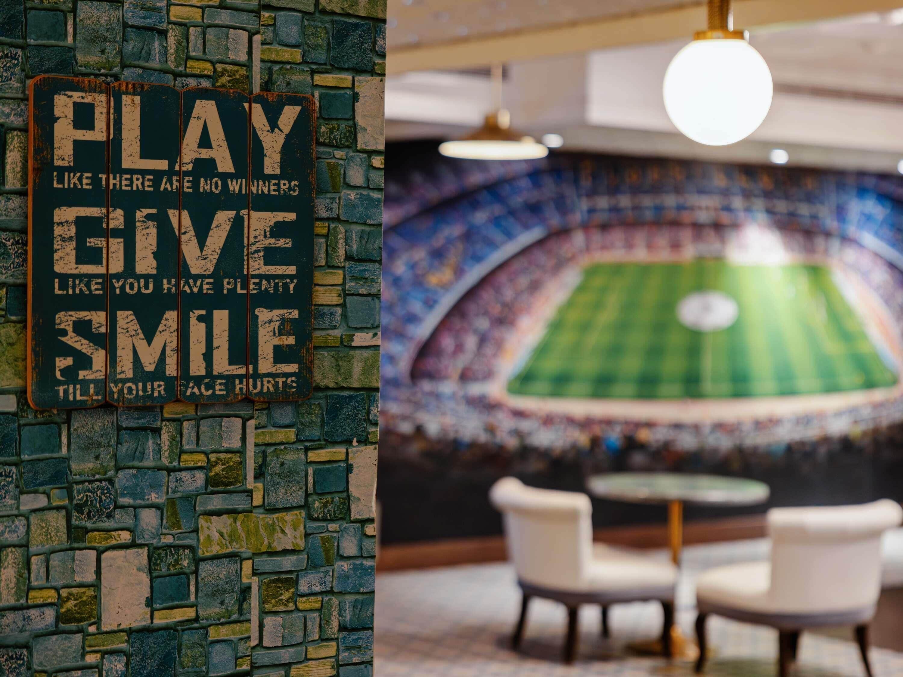 A wall with a motivational quote and a stadium-themed mural.