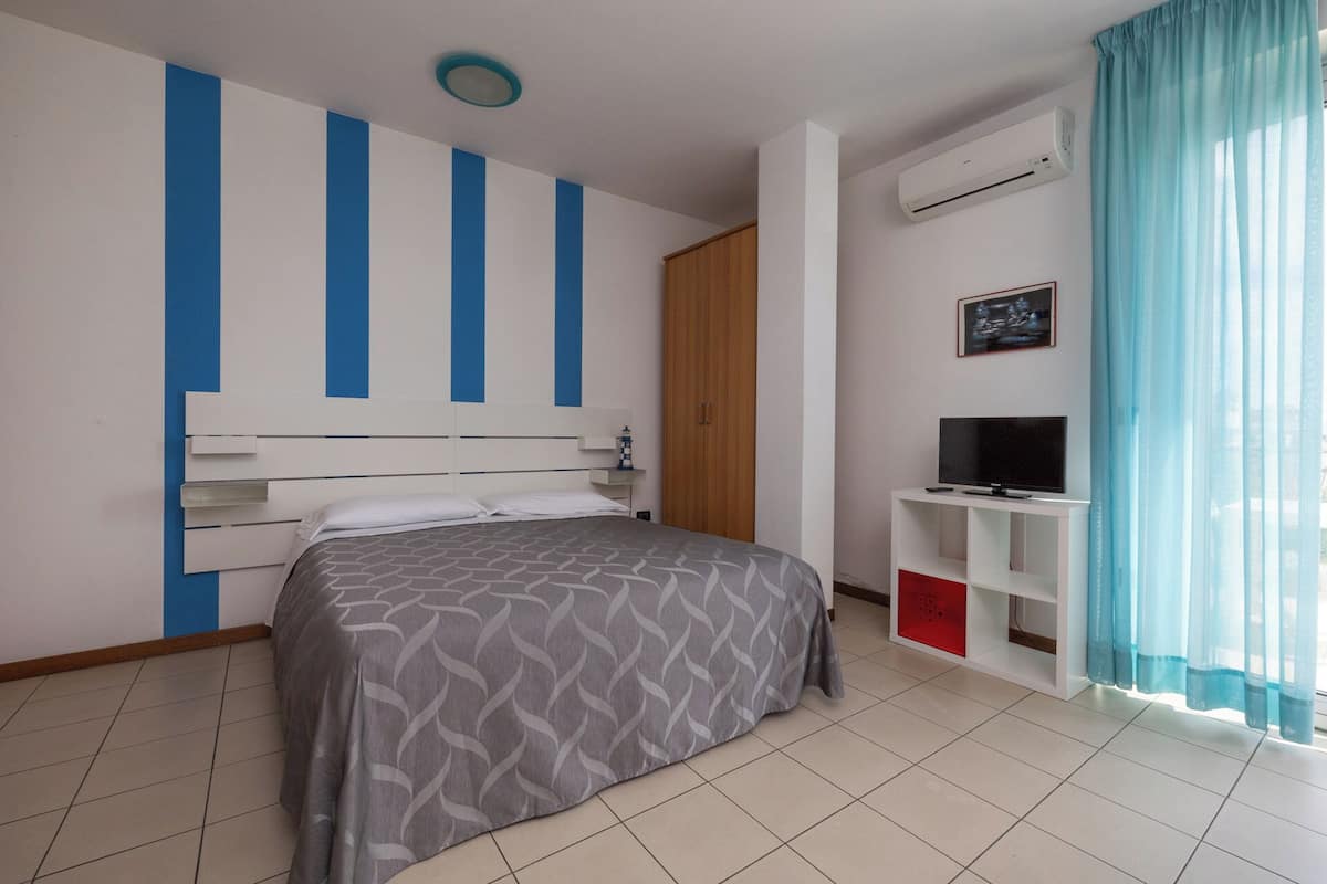 Ein Schlafzimmer mit einem Bett, einem Fernseher, einer Klimaanlage und einem Kleiderschrank.