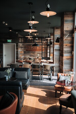 A modern interior with wooden walls, multiple seating areas, and pendant lighting. - Coffee Fellows Hotel Trier (Trier)