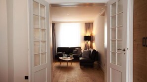 Una habitación de hotel con piso de madera, un sofá, una mesa de centro y una lámpara.