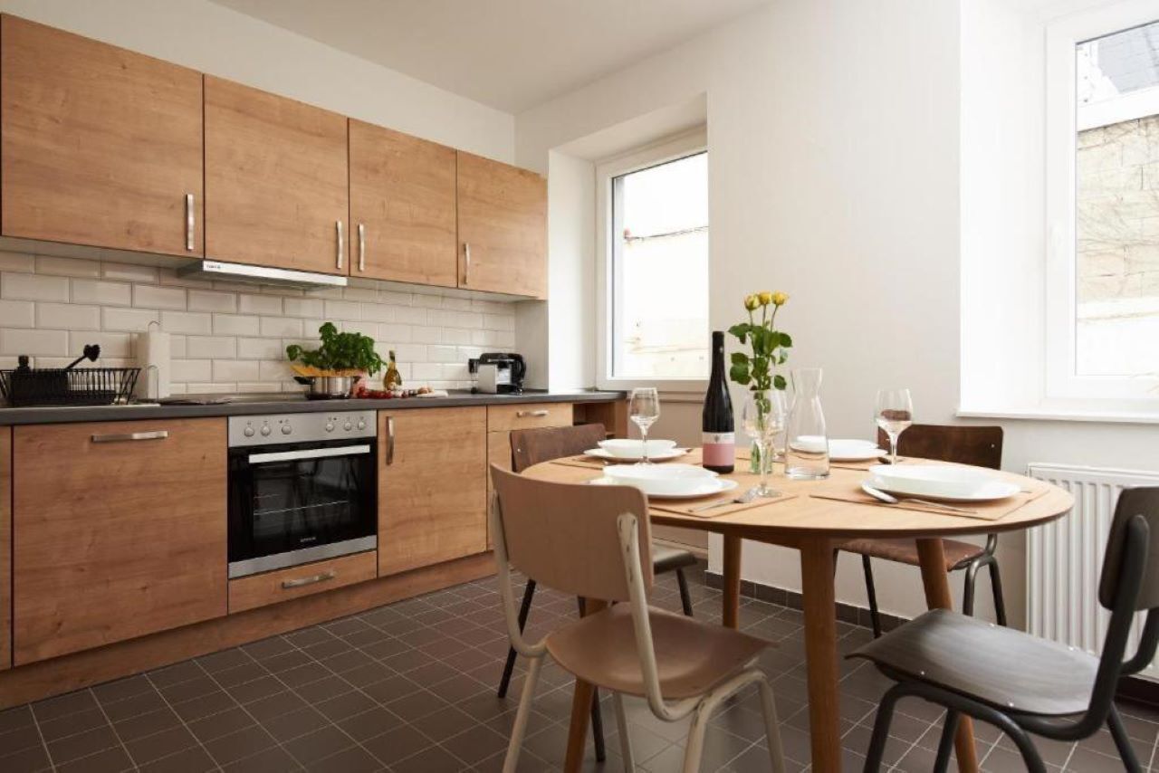 Eine moderne Küche mit Holzausbau, einem eingebauten Backofen und einem Essbereich mit rundem Tisch und Stühlen.