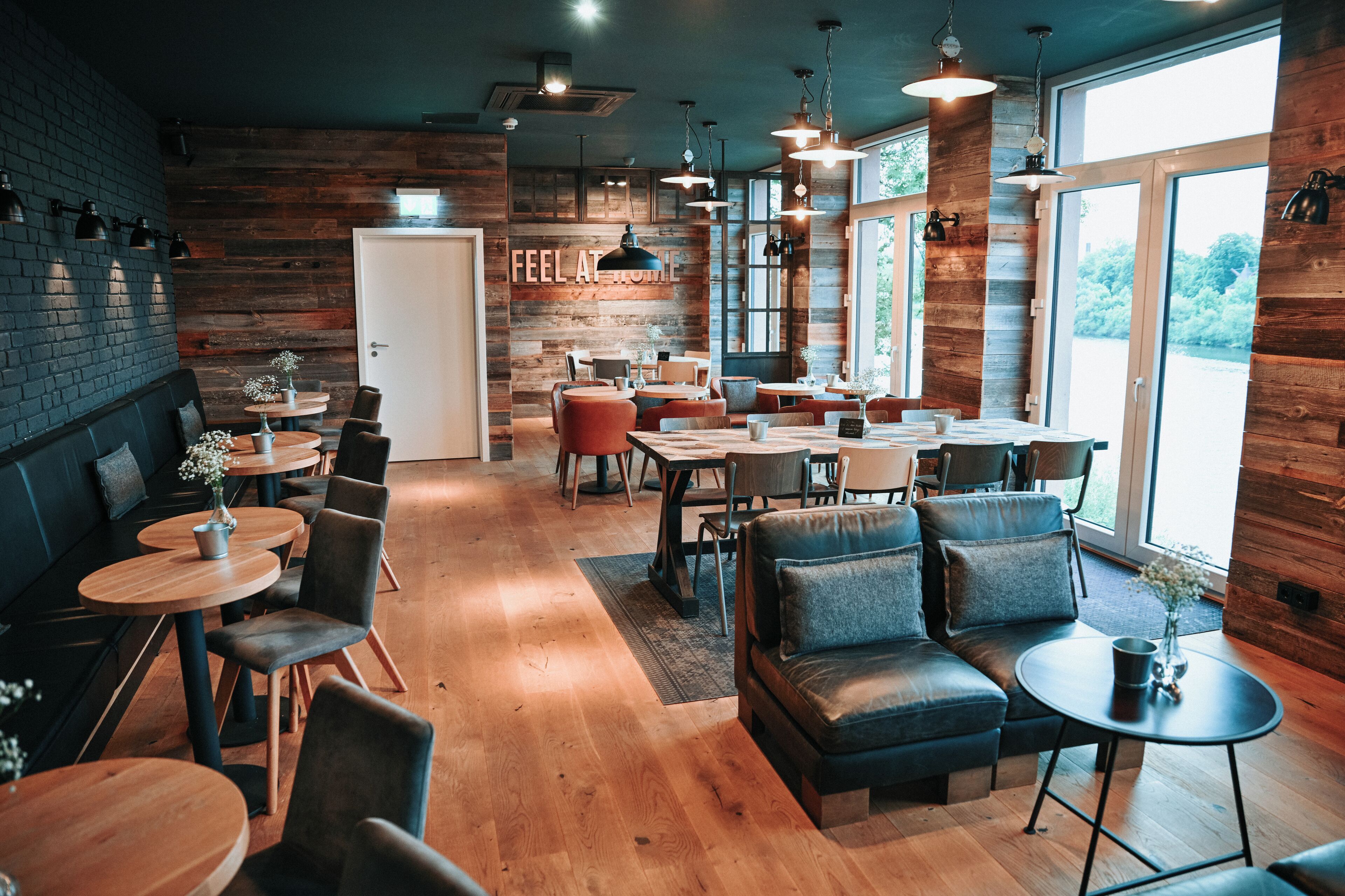 Ein gemütliches Restaurant mit Holzwänden, runden Tischen und bequemen Sitzgelegenheiten.