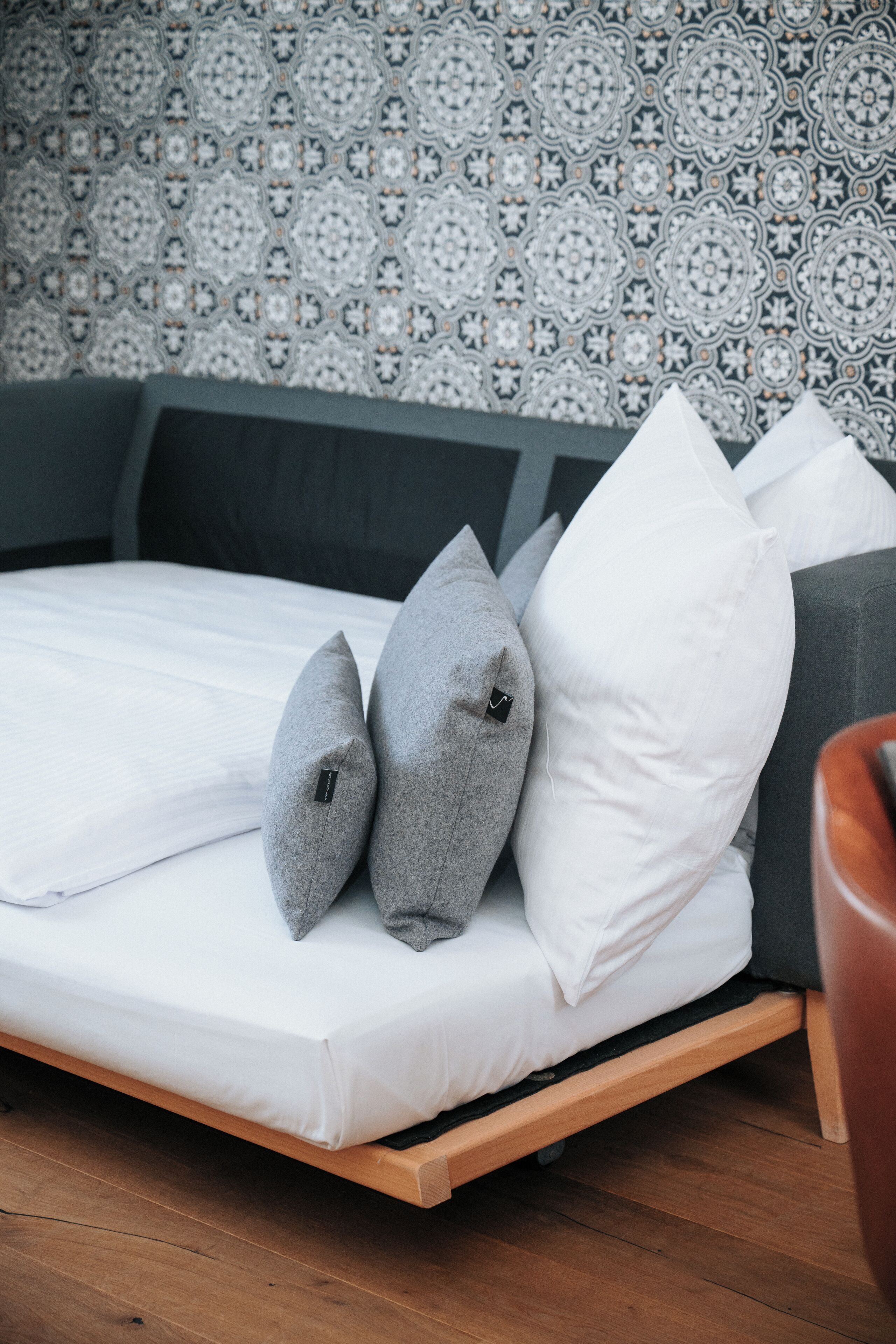 A bed with a wooden frame, grey upholstered headboard, and white bedding.