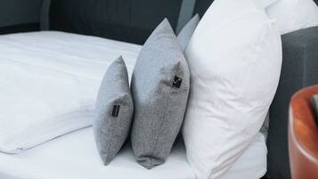 Een bed met houten frame, grijs bekleden hoofdeinde en witte beddengoed.