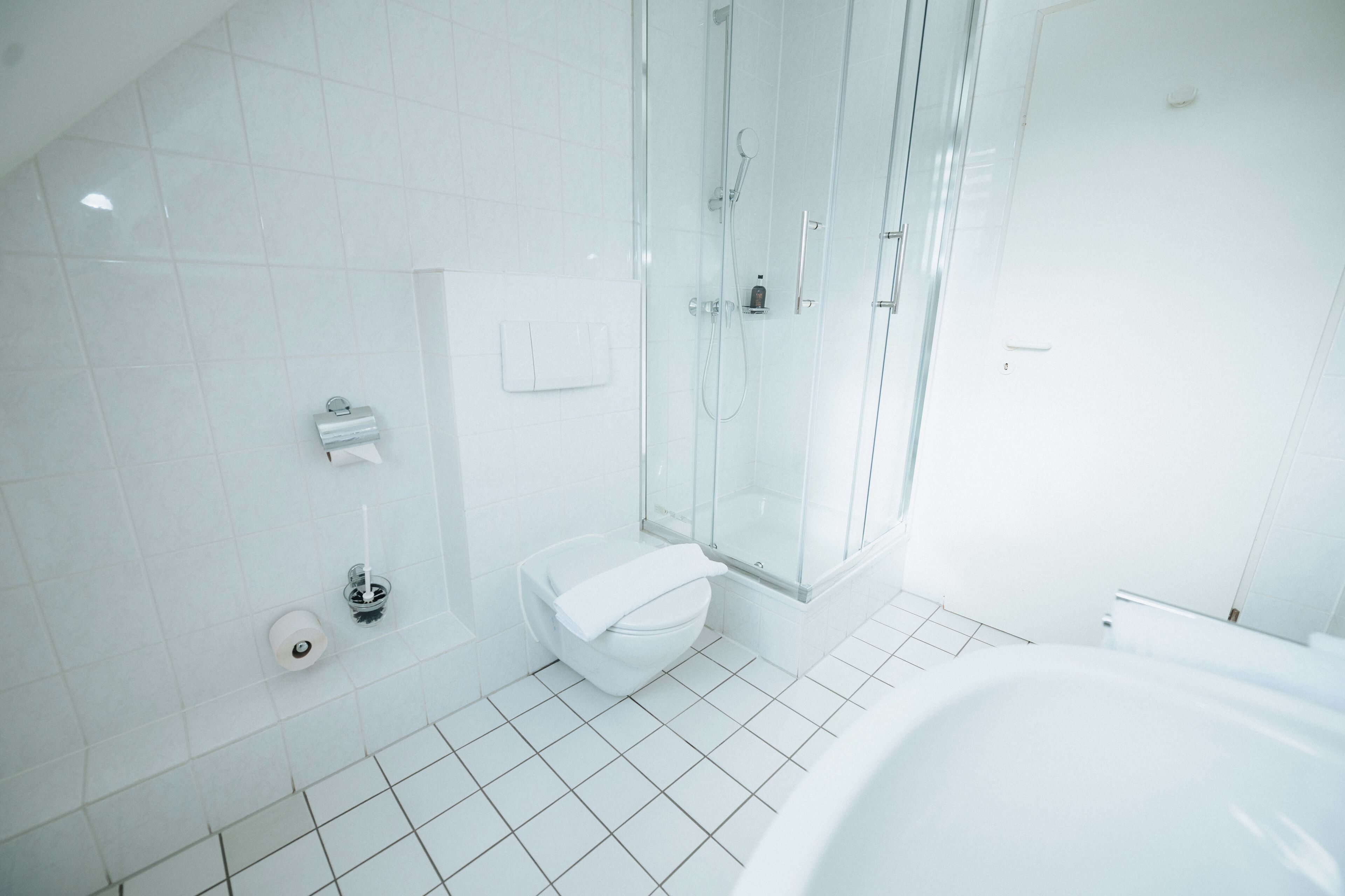 Ein modernes Badezimmer mit einer Duschkabine, einer weißen Toilette und einer großen Badewanne.
