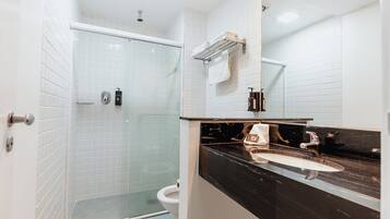 A modern bathroom with a glass-enclosed shower, a white toilet, and a black countertop sink with a mirror above it.