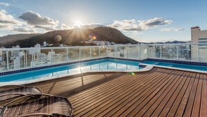 A rooftop pool with a wooden deck and glass railings. - Victory Suites (Juiz de Fora)