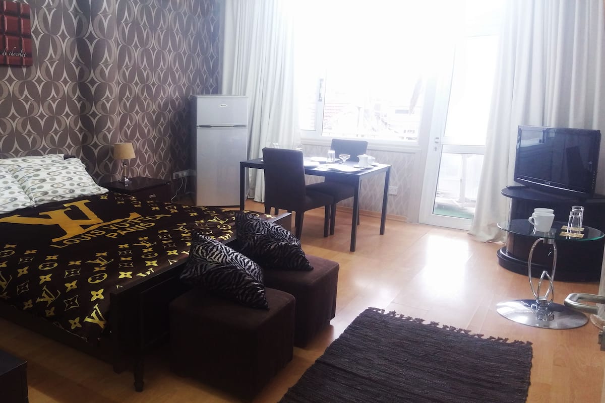 Una habitación de hotel con cama, escritorio, silla, televisor y mesa de centro.