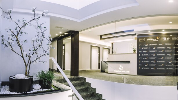 Un moderno vestíbulo de hotel con un mostrador de recepción, una escalera y una decoración floral.