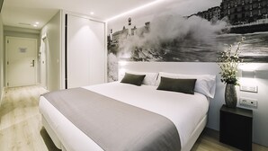 Una habitación de hotel moderna con una cama grande, una mesita de noche con un florero y un mural en la pared de un paisaje urbano.