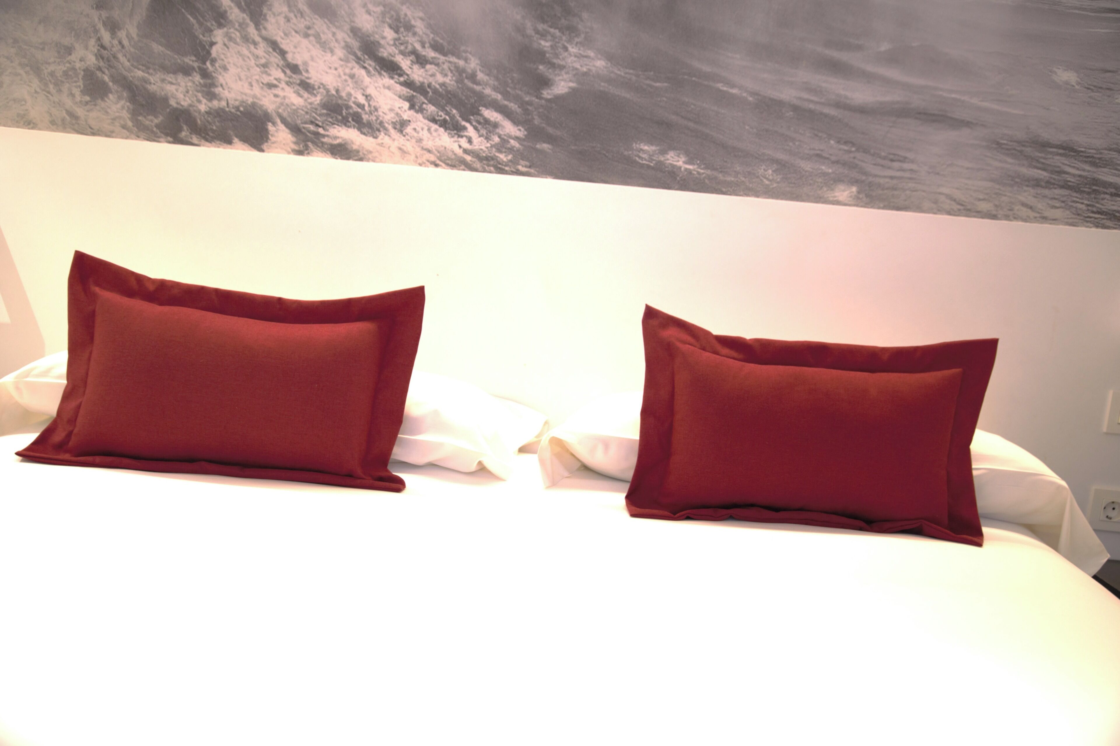 A bed with two red pillows and a white bedspread.