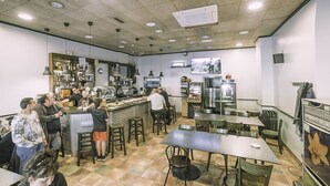 Un restaurante con zona de bar, varias mesas y sillas.