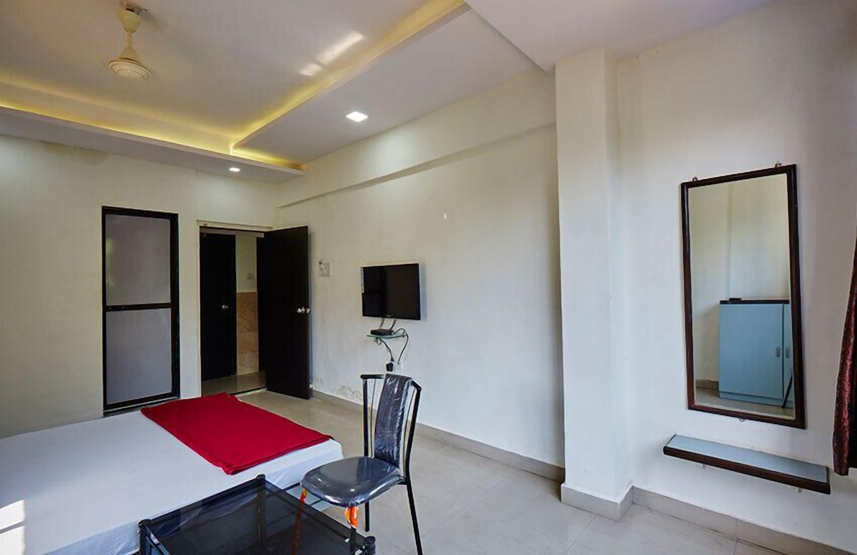 A hotel room with a bed, a chair, a TV, and a mirror.