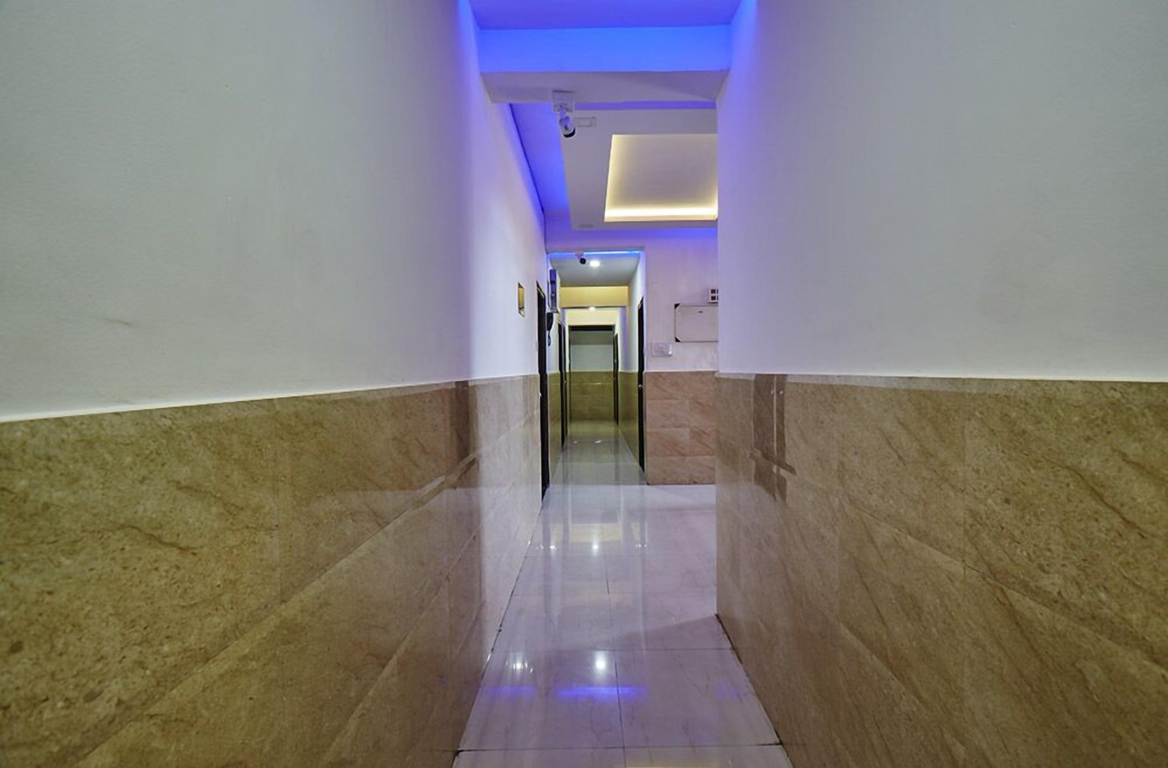 A hallway with marble walls and a reflective floor, leading to a room with a door at the end.