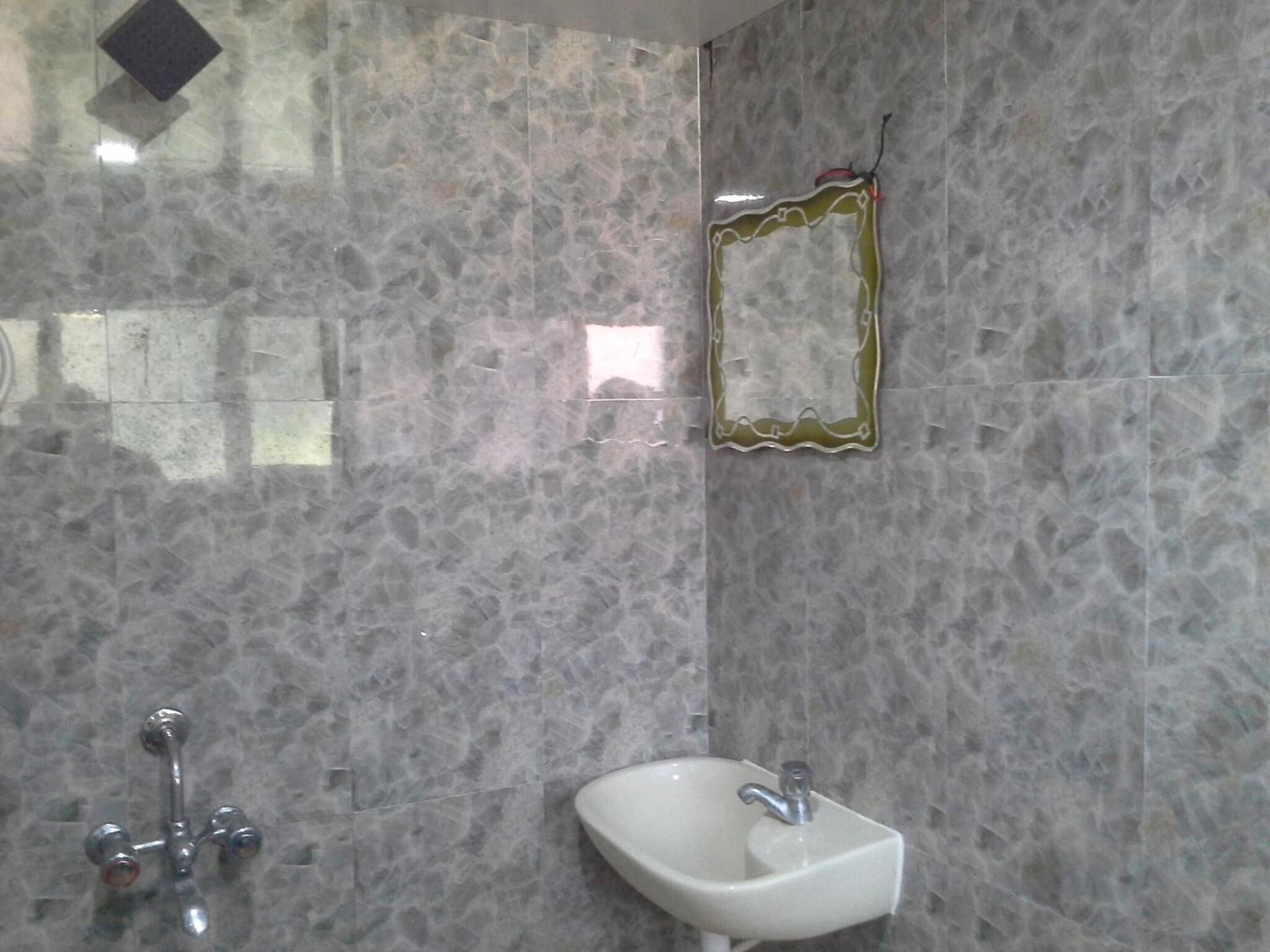 Une salle de bain avec un mur en marbre, un lavabo et un miroir.