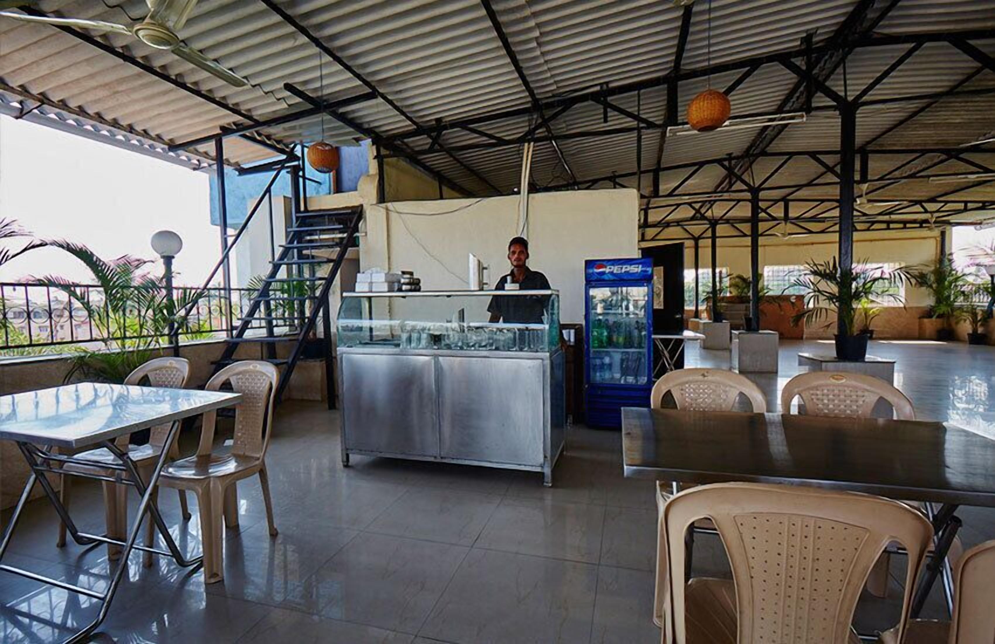 An outdoor dining area with a counter, chairs, and a Pepsi refrigerator.