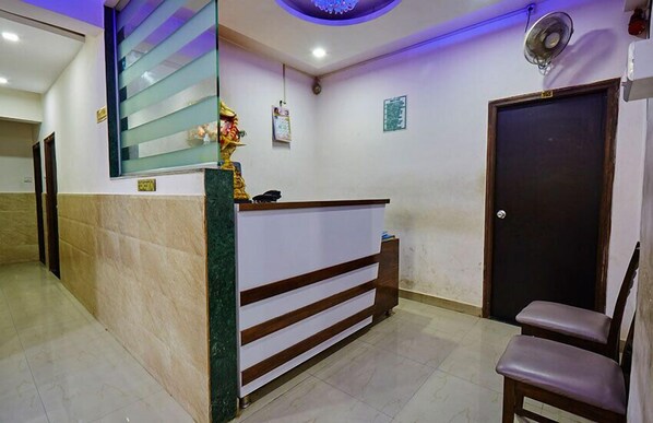 Un área de recepción con un mostrador de mármol, un ventilador de pared, una puerta y una silla.