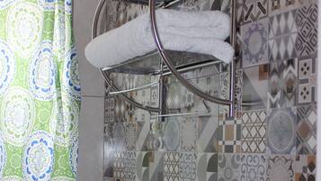 A bathroom with a patterned tile backsplash, a white sink, a towel rack, and a shower curtain.