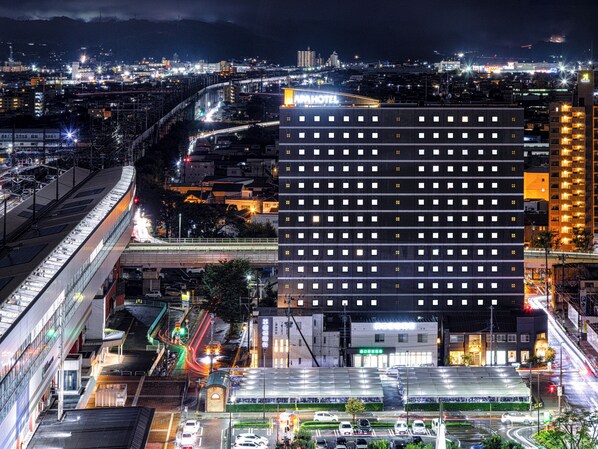 A modern hotel with a prominent "HOTEL" sign, surrounded by a busy urban environment with visible traffic and infrastructure.
