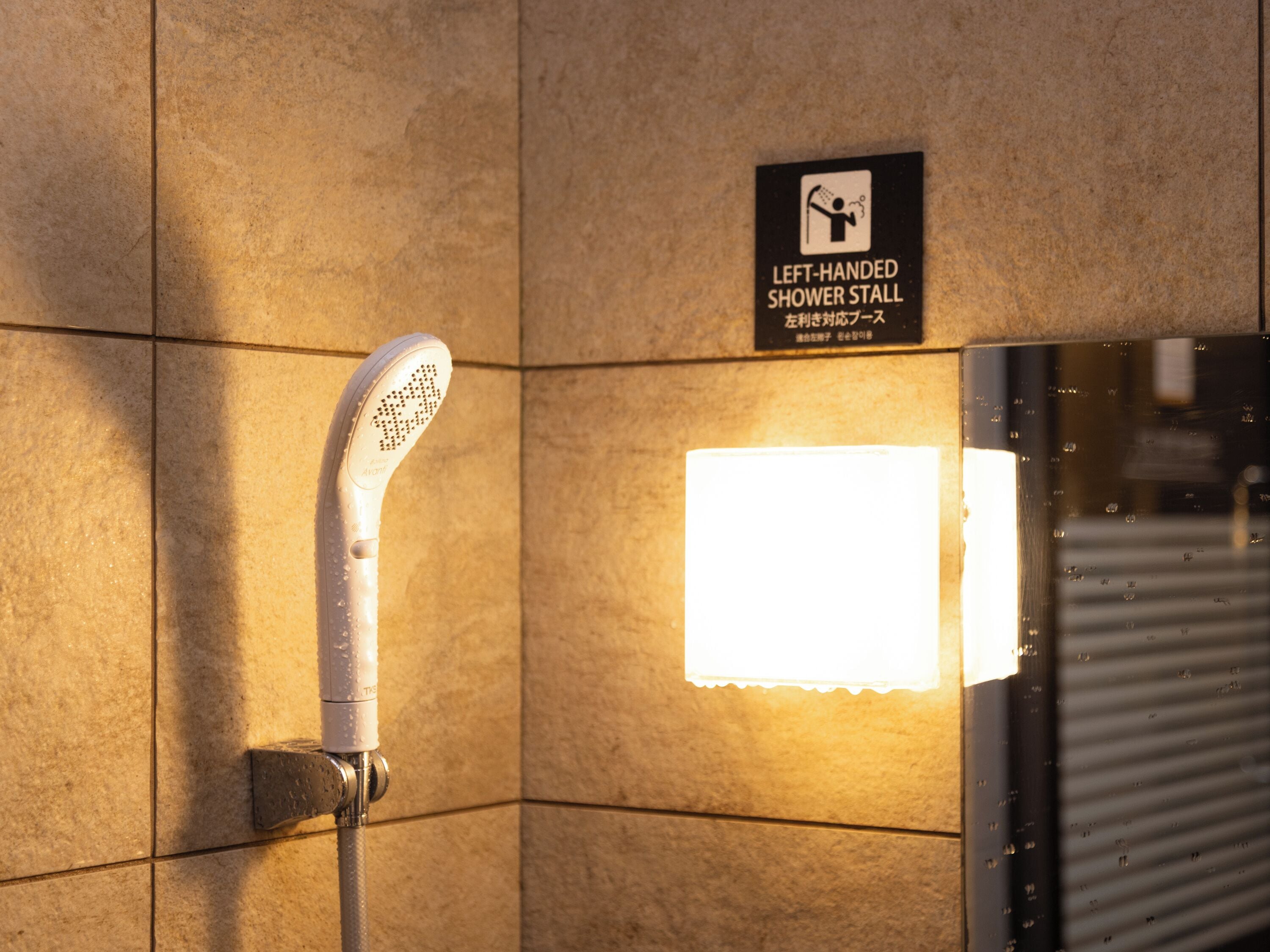 A left-handed shower stall with a sign indicating its use.