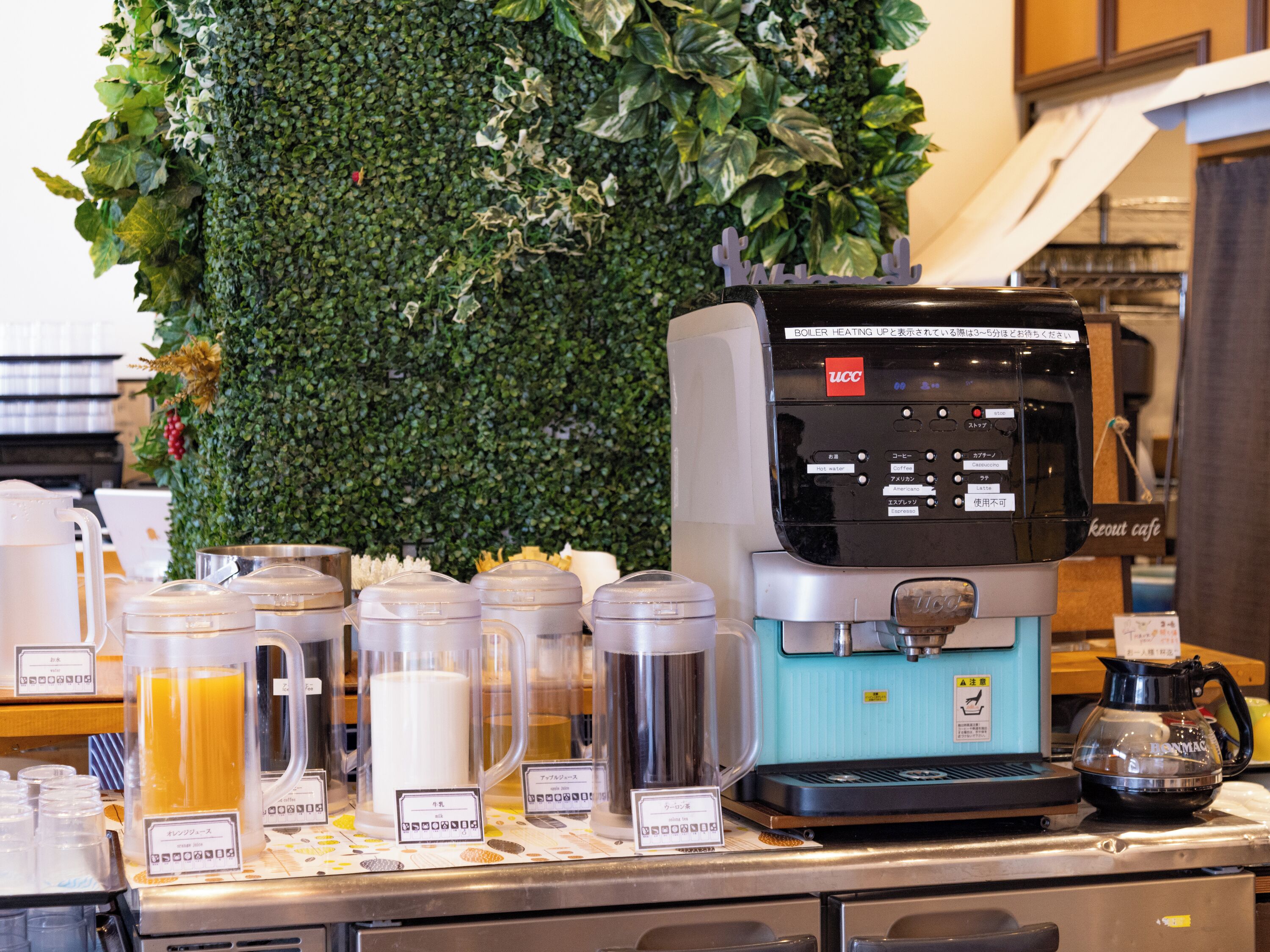 Una estación de café con una cafetera, dispensadores de leche y varios recipientes para café.