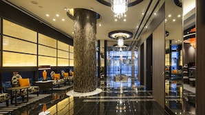 A spacious lobby with a large column, a chandelier, and a seating area with patterned chairs. - APA Hotel Fukushima Ekimae (Fukushima)