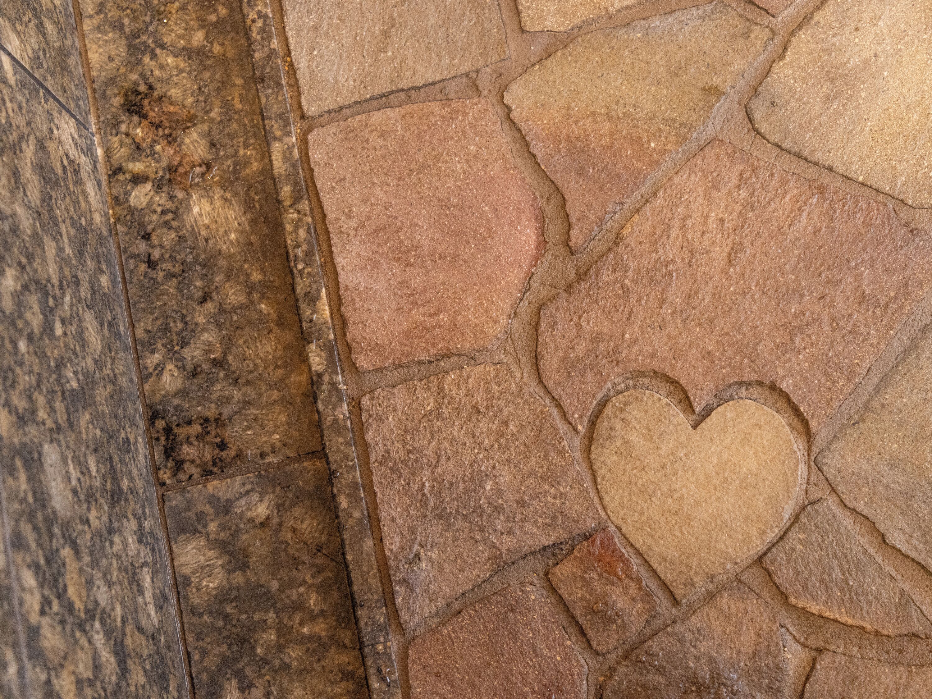 A close-up of a stone floor with a heart-shaped cutout.