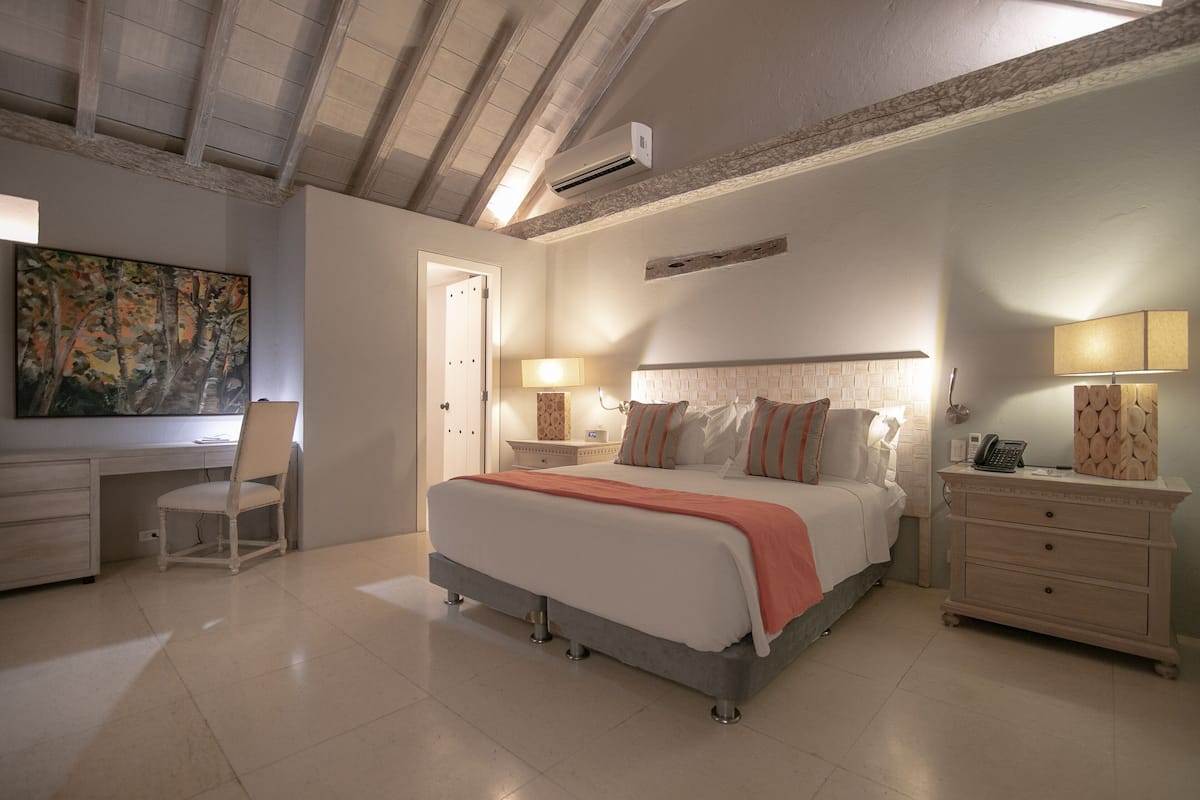 A bedroom with a bed, bedside tables, a desk, and a chair.