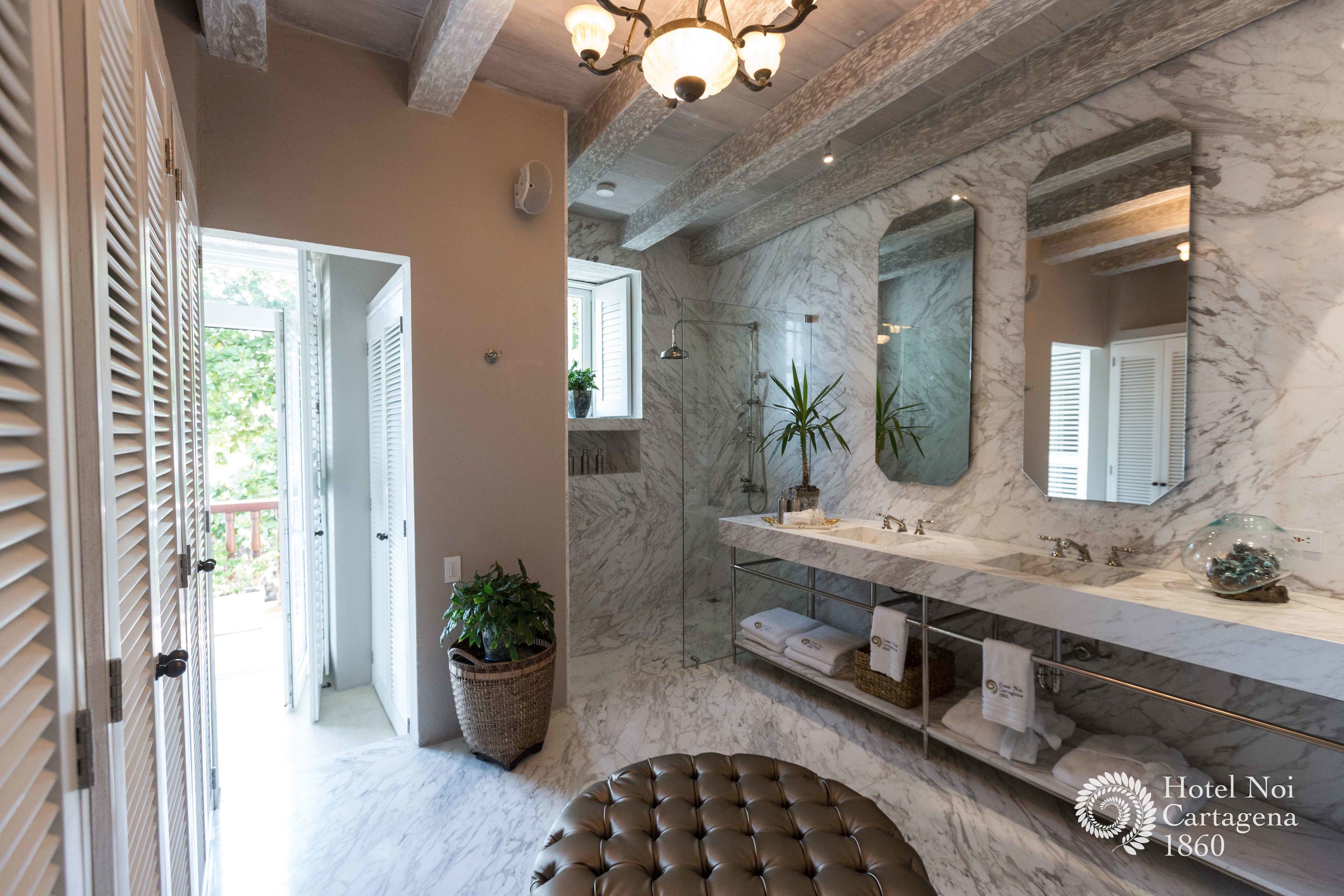 A modern bathroom with marble walls, a large mirror, and a vanity with multiple sinks.