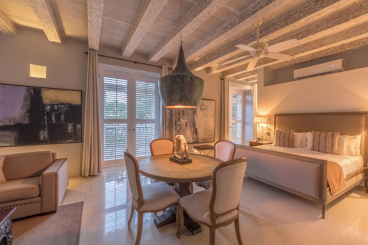 A spacious living room with a round dining table, a sofa, and a large bed.