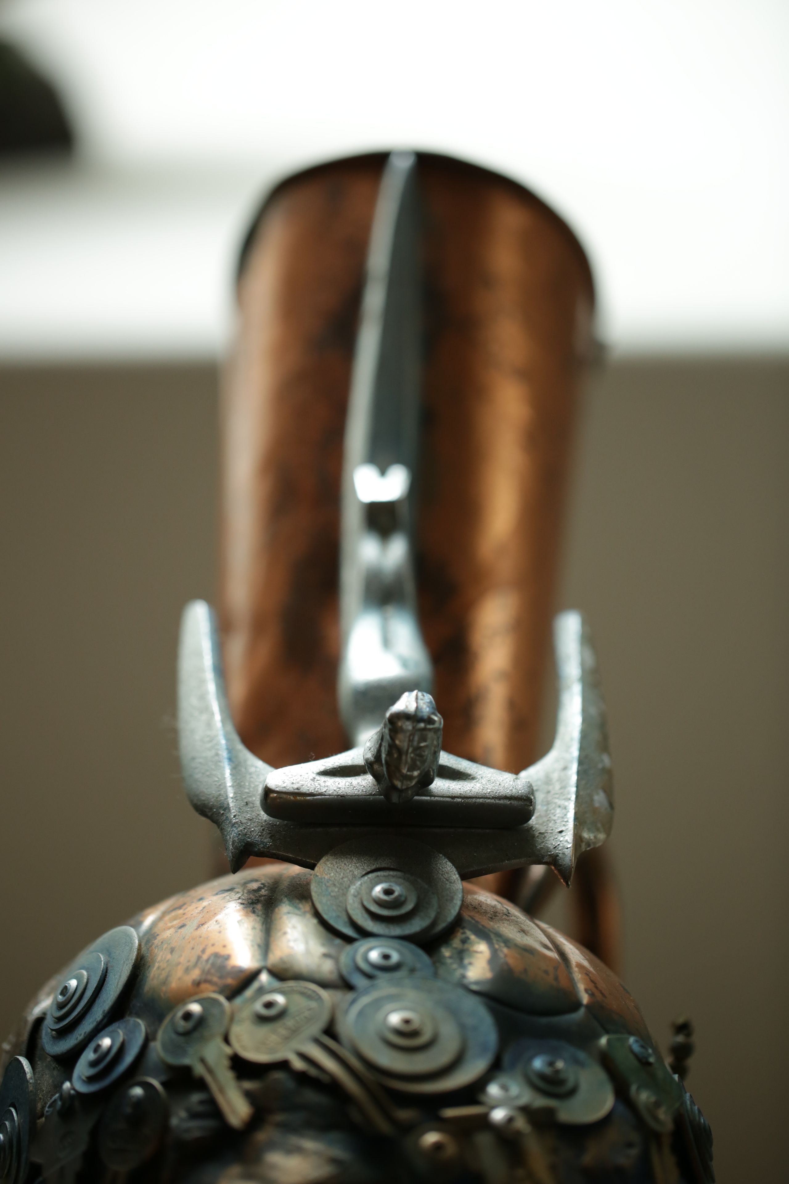 A close-up of a metallic object with a handle and decorative elements.