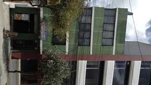A building with a green facade, large windows, and a sign for a restaurant.