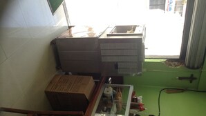 A room with a tiled floor, a large window, a radiator, a table with various items, and a green wall.