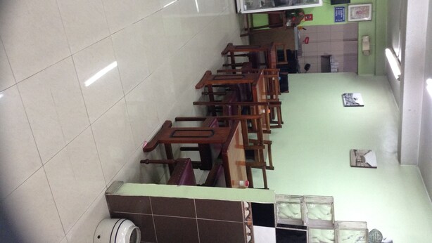 A classroom with wooden desks and chairs, a projector screen, and a tiled floor.