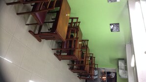 A restaurant interior with wooden tables and chairs, a green wall, and a tiled floor.