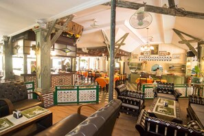A restaurant with wooden beams, brick walls, and a mix of seating including booths and tables. - Sendok Hotel (Senggigi)
