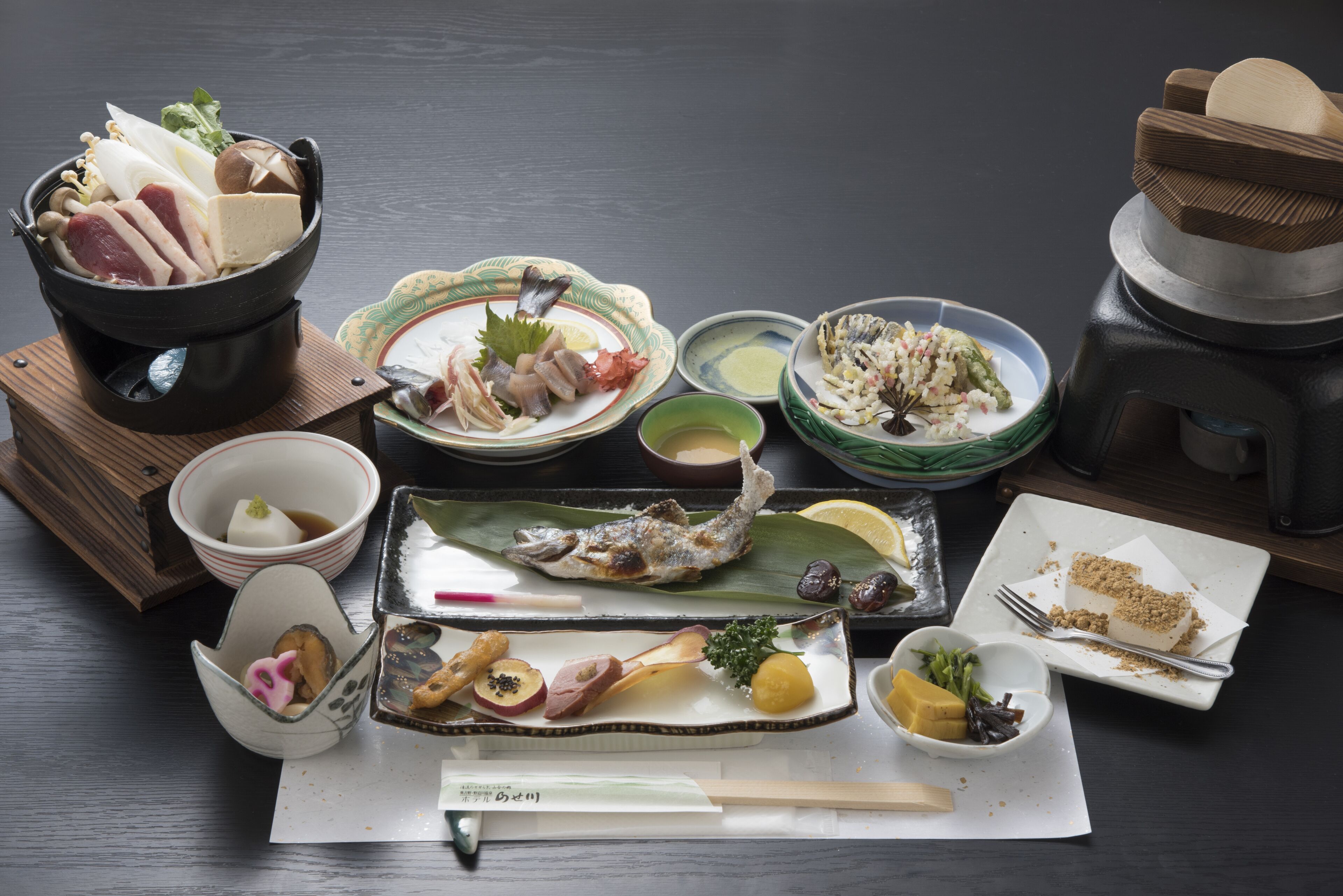 A variety of dishes including fish, vegetables, and a dessert on a table.