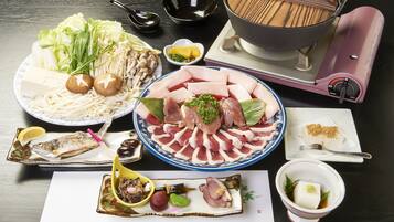 Variedad de platos que incluyen fideos, sashimi y mariscos, dispuestos sobre una mesa con un recipiente caliente y palillos.