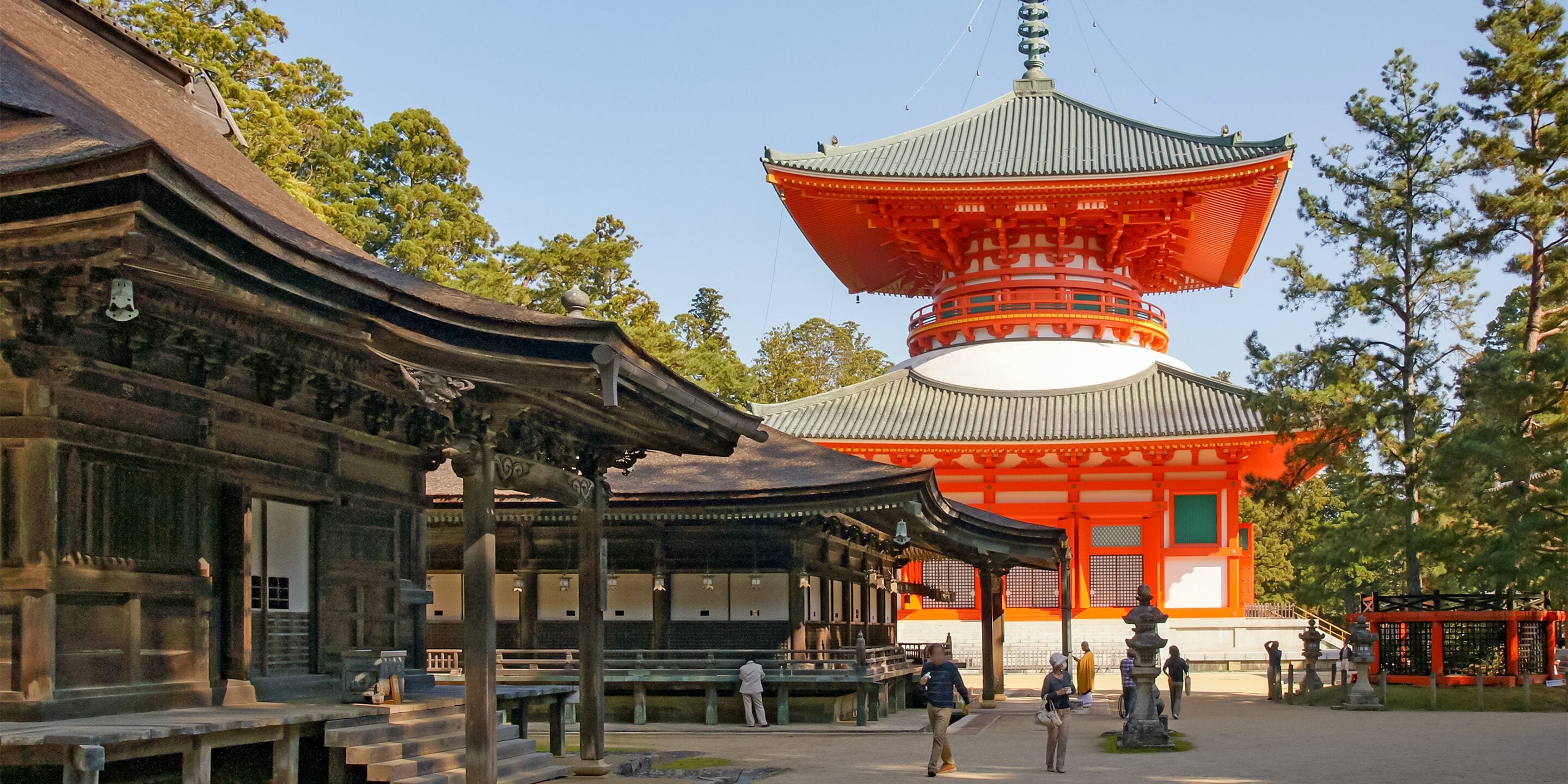 Ein traditioneller japanischer Tempel mit einer großen, roten Pagode und einem Holzgebäude mit geschwungener Dachform.