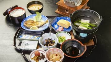 A variety of Japanese dishes including rice, fish, tofu, and pickled vegetables on a tray.