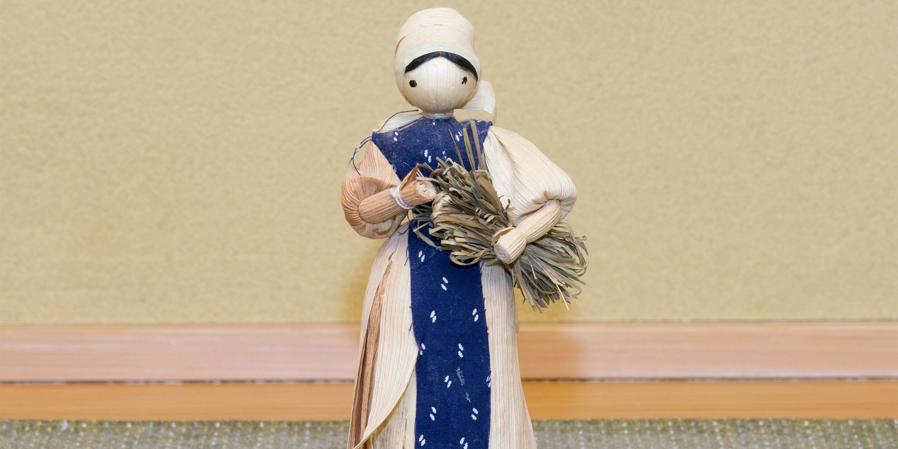 Una nina amb un vestit blau i blanc, subjectant un ram d'espart.