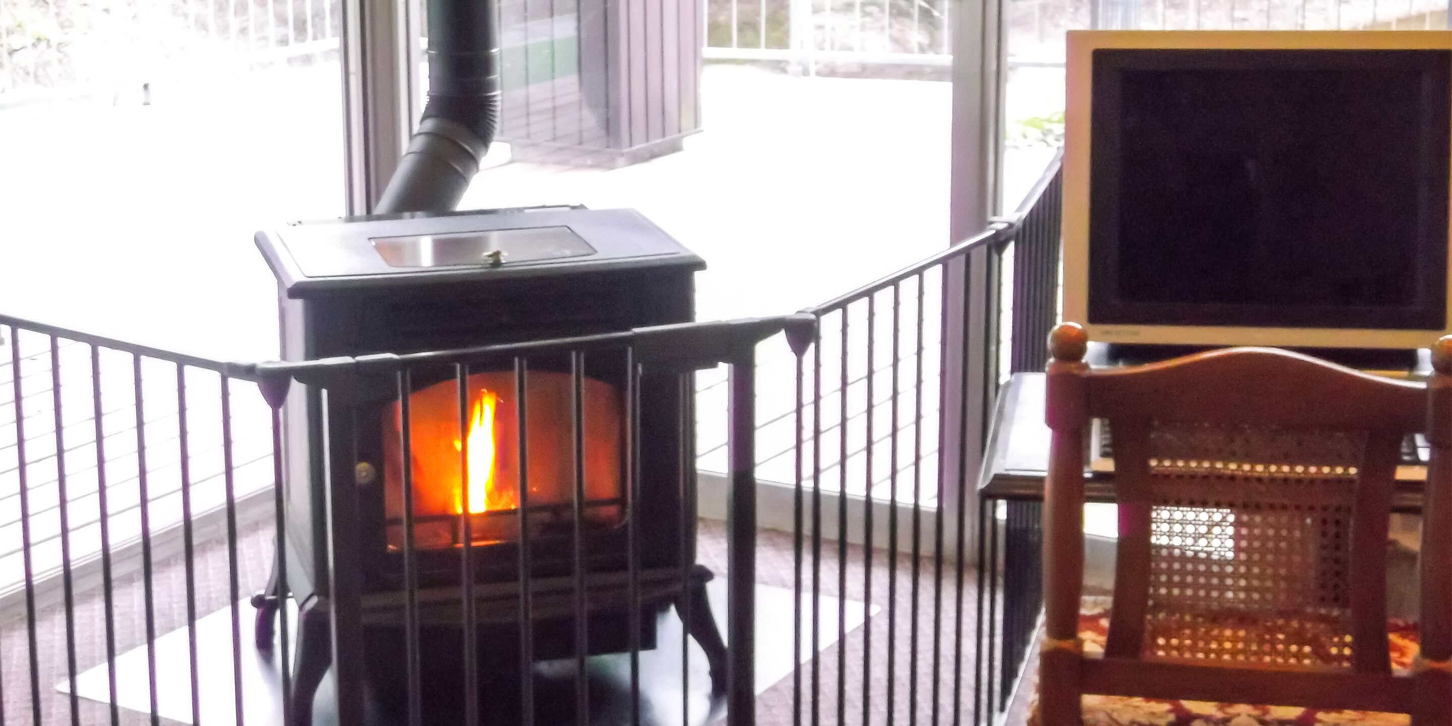 A wood-burning stove with a visible fire, a chair, and a television.