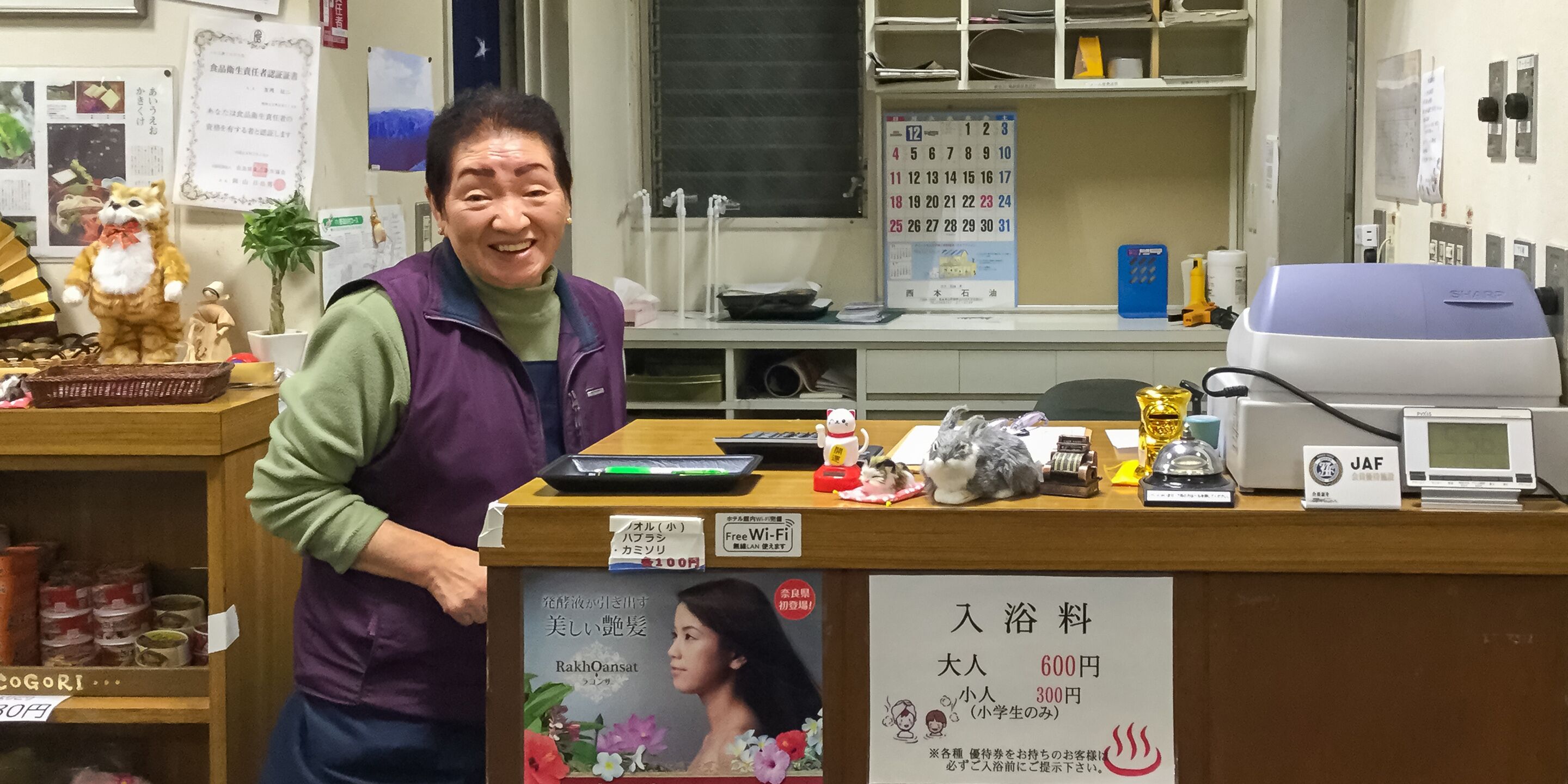 A reception desk with a calendar, a computer, and various items on the counter.