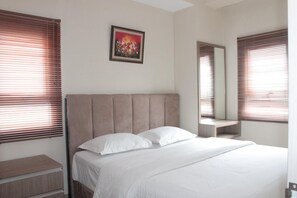 A bedroom with a bed, a nightstand, a mirror, and a painting on the wall.